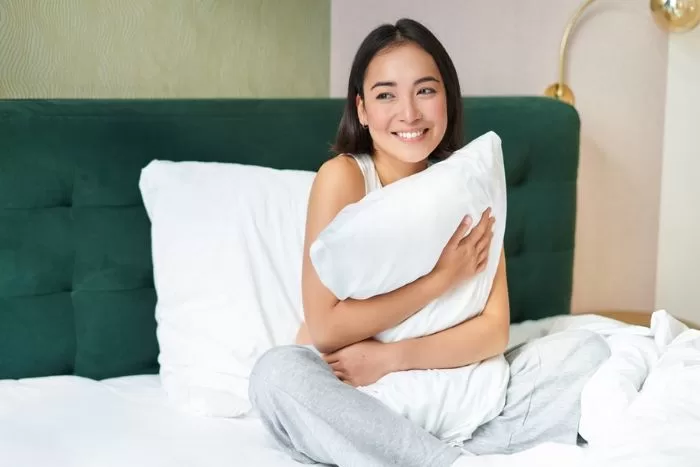 mulher sentada na cama segurando um travesseiro