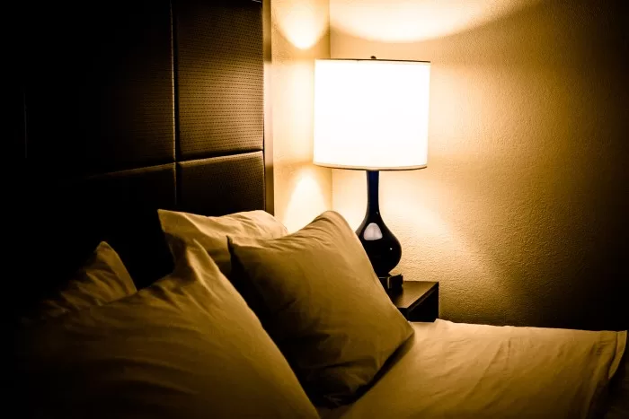 Quarto com luz quente em abajour, ao lado da cama.