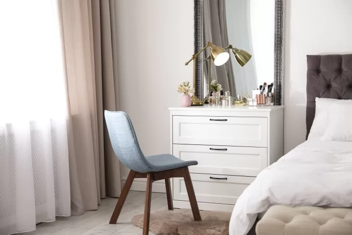 Quarto personalizado com penteadeira e cômoda ao lado da cama.