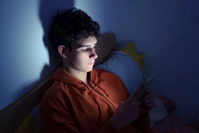 Jovem mexe no celular antes de dormir.