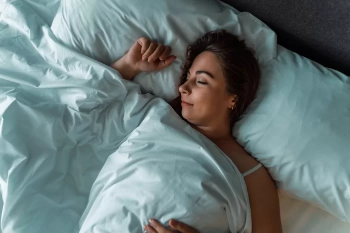 Mulher dormindo de barriga para cima.