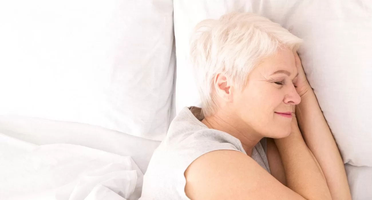 Senhora dormindo de lado em colchão.