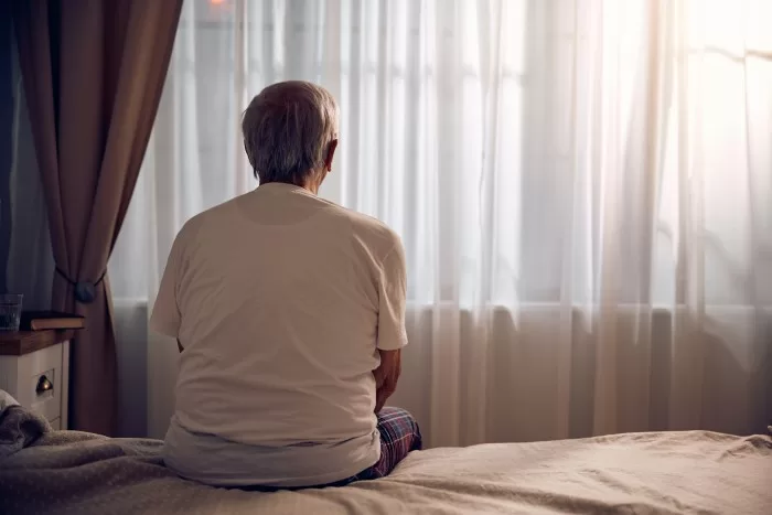 Senhor sentado no colchão.