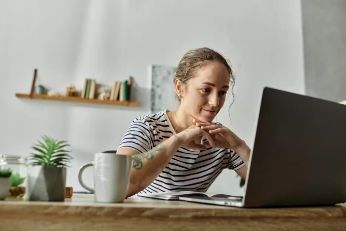 Mulher trabalhando em computador com xícara de café.