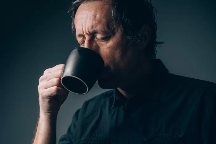 Homem tomando café durante a noite.