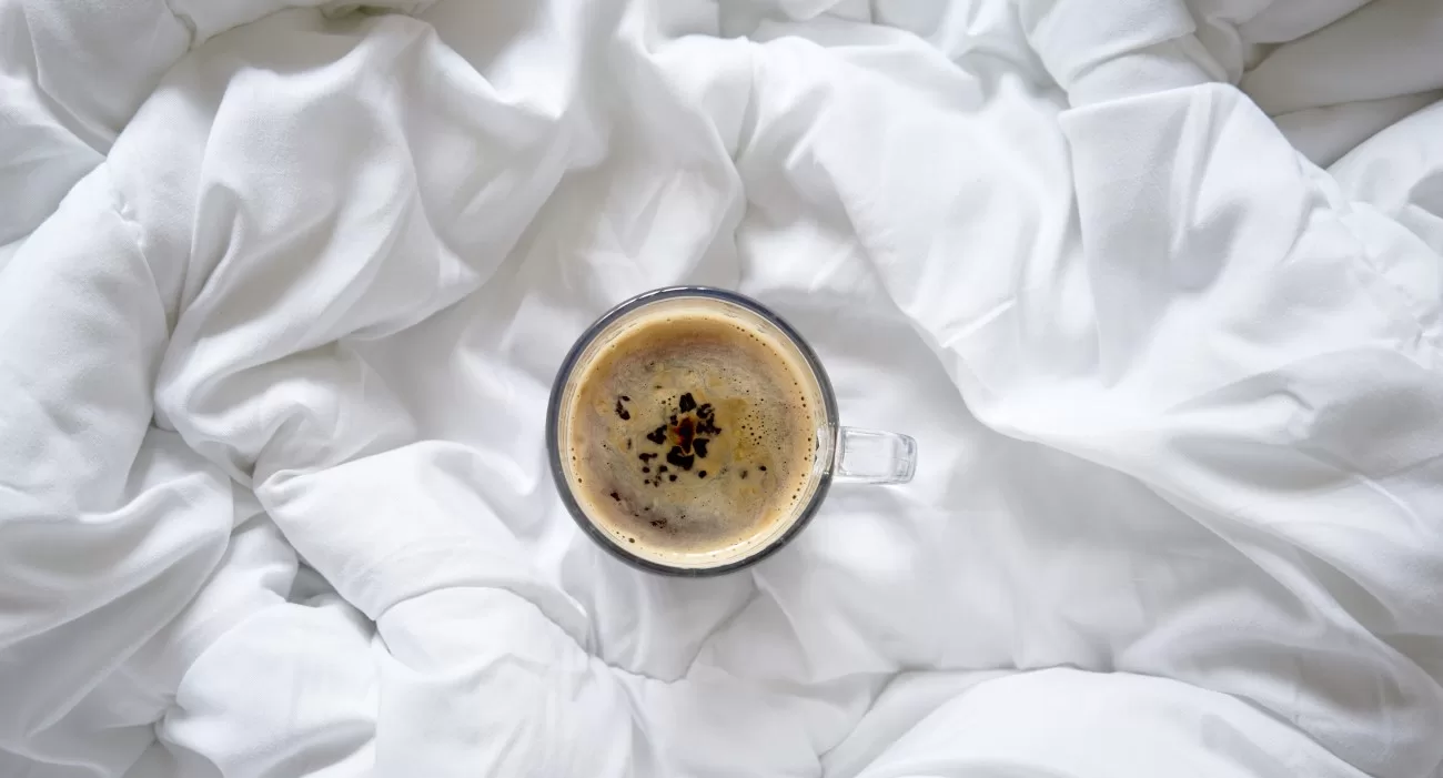 Xícara de café sobre cama.