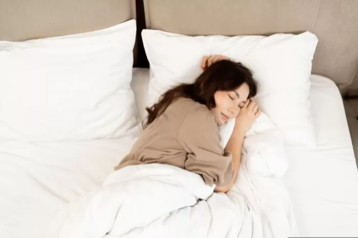 Mulher dormindo em uma cama com travesseiro.