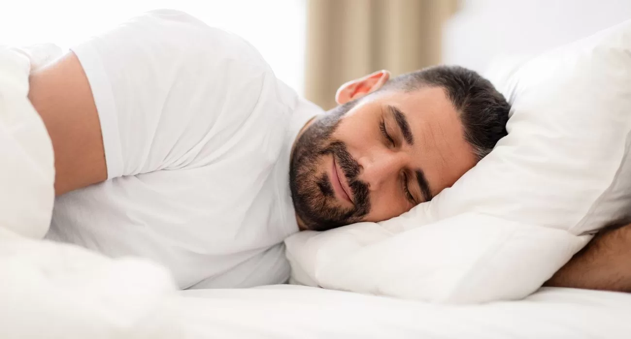 Homem dormindo em uma cama com travesseiro.