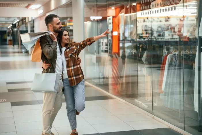 Compradores apontam para vitrine em shopping.