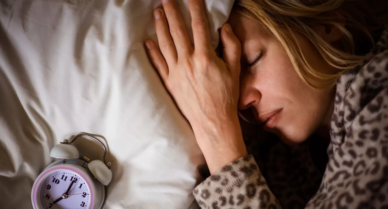 Mulher dormindo com despertador.