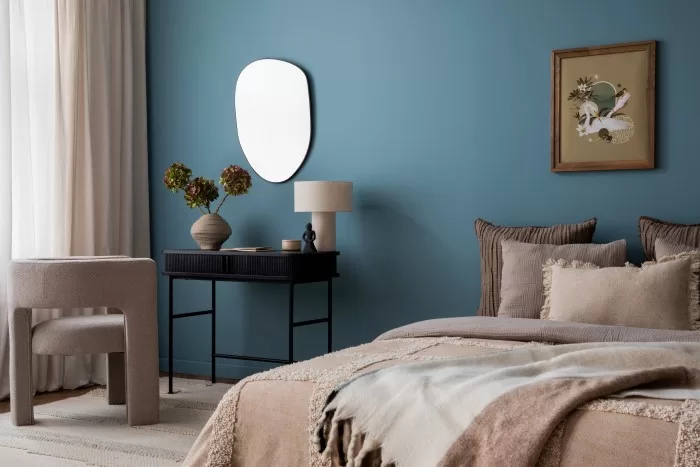 Quarto com a parede azul e decoração em bege.