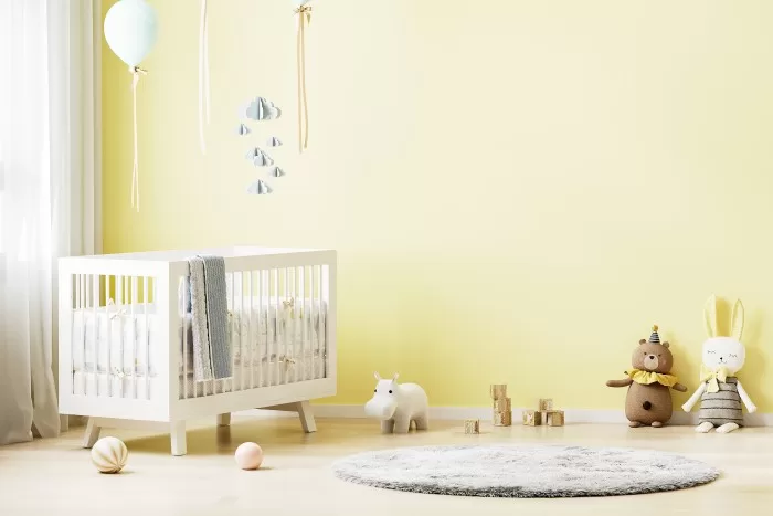 Quarto de bebê pintado de com parede amarela.