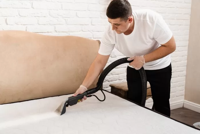 Homem aspirando um colchão