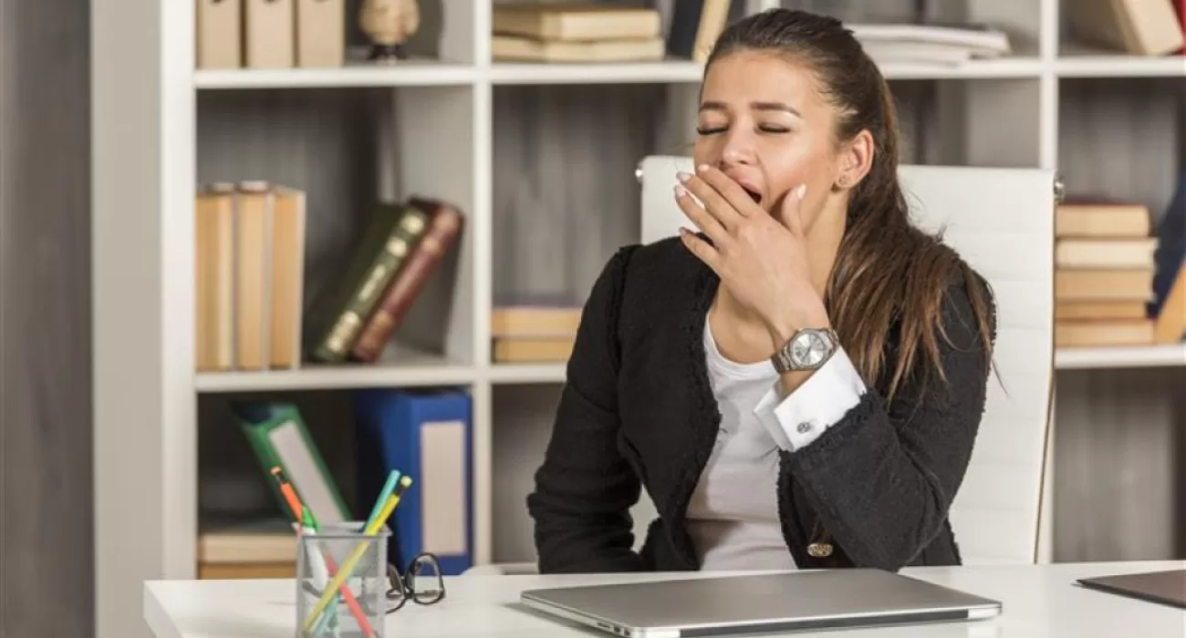 Mulher sentada bocejando em um escritório