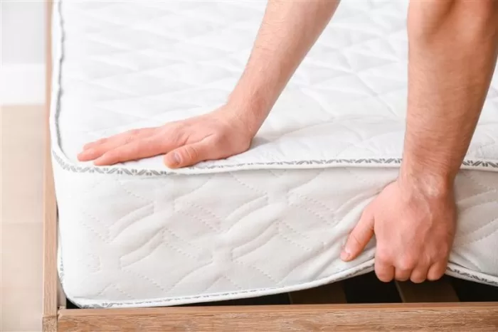 Mãos de um homem tocando no colchão