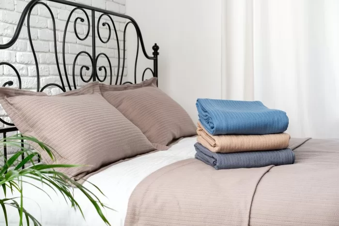 Uma cama arrumada com lençóis dobrados em cima.