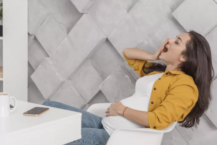 Mulher grávida sentada bocejando