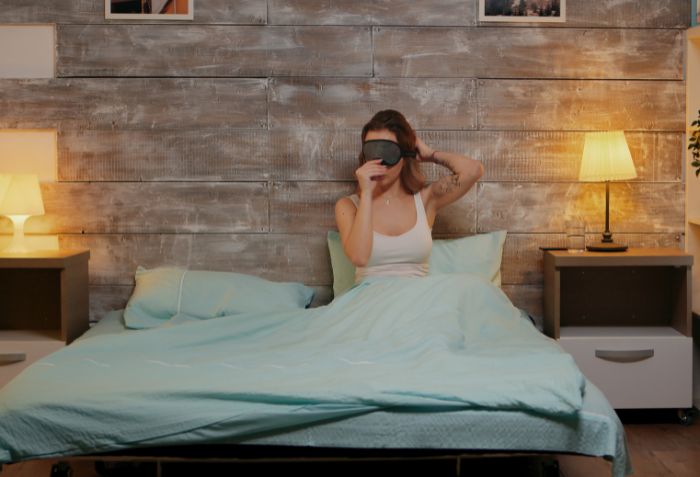 Mulher na cama descansando com luzes indiretas.