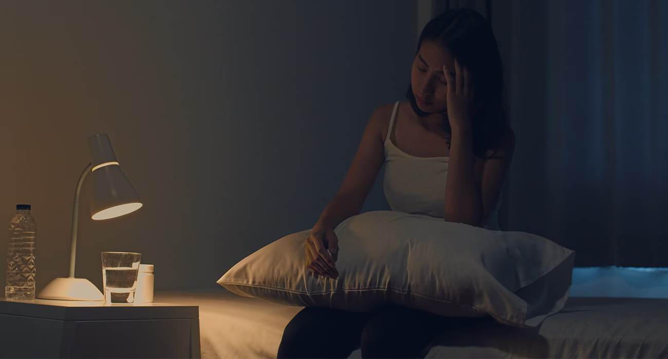 mulher sentada na cama suando: quando o suor noturno é preocupante?